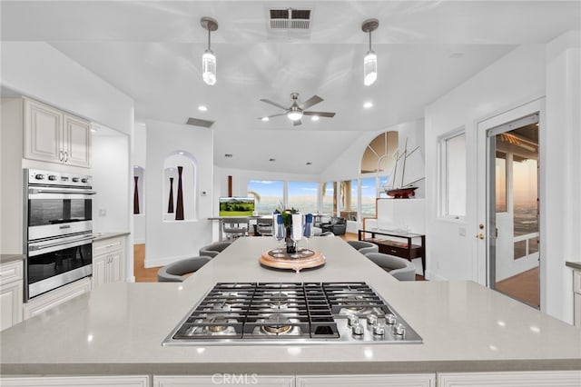 kitchen featuring ceiling fan, a center island, hanging light fixtures, and appliances with stainless steel finishes