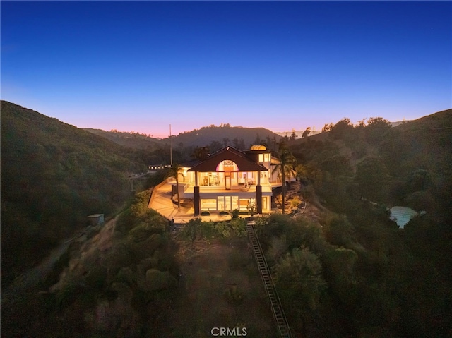 back house at dusk with a mountain view and a balcony