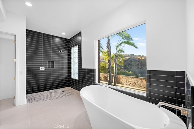 bathroom with tile patterned flooring, a bathing tub, and tile walls