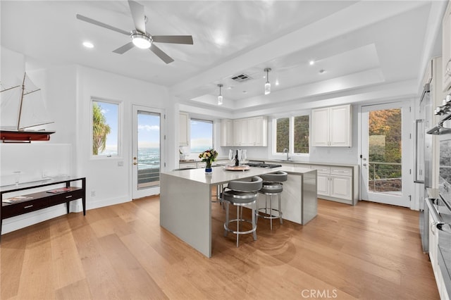 kitchen featuring a breakfast bar, a center island, white cabinetry, and light hardwood / wood-style flooring