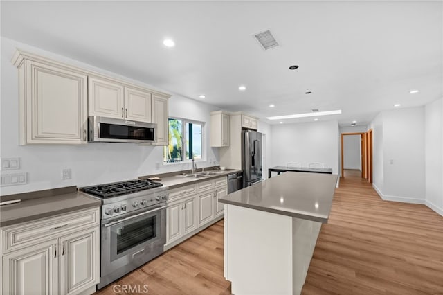 kitchen featuring a center island, cream cabinets, sink, light wood-type flooring, and stainless steel appliances