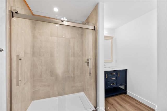 bathroom with hardwood / wood-style floors, vanity, and a shower with shower door