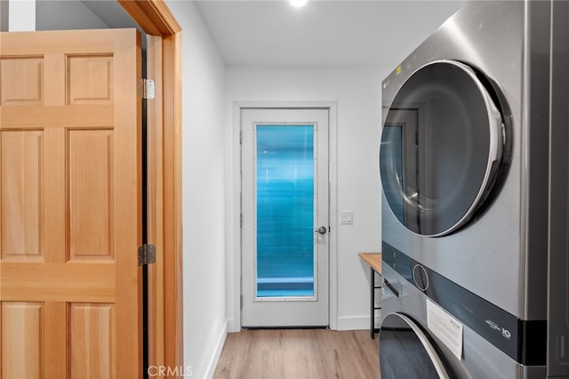 clothes washing area with stacked washer and dryer and light hardwood / wood-style flooring