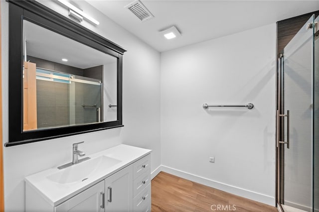 bathroom featuring hardwood / wood-style floors, vanity, and a shower with door