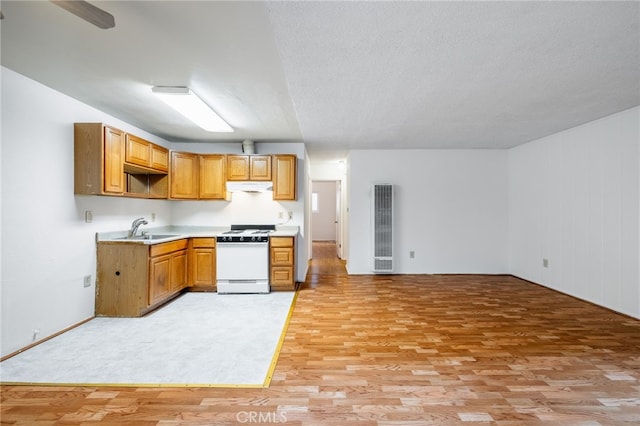 kitchen with a textured ceiling, sink, white gas range oven, and light hardwood / wood-style floors