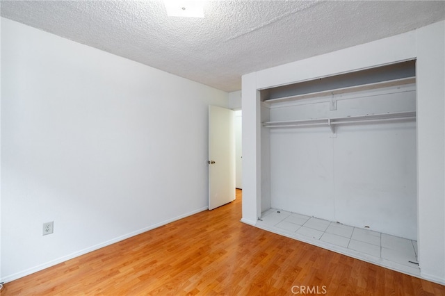 unfurnished bedroom with light hardwood / wood-style floors, a textured ceiling, and a closet