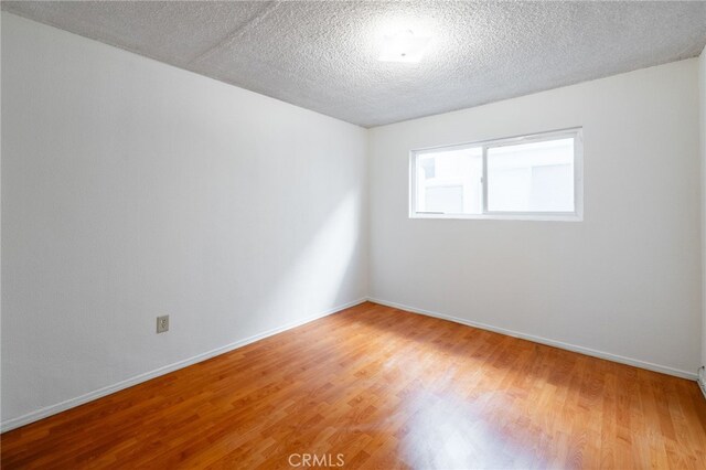 spare room featuring a textured ceiling and hardwood / wood-style flooring