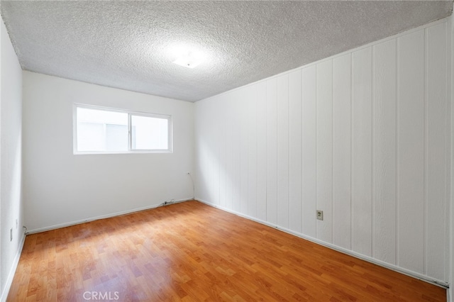 empty room with hardwood / wood-style flooring and a textured ceiling