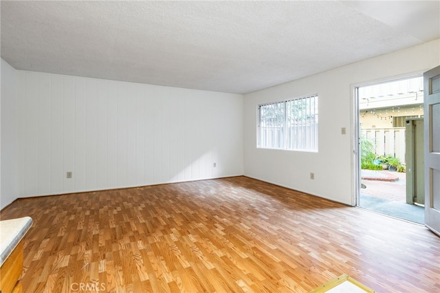 empty room featuring hardwood / wood-style floors, wood walls, and a textured ceiling