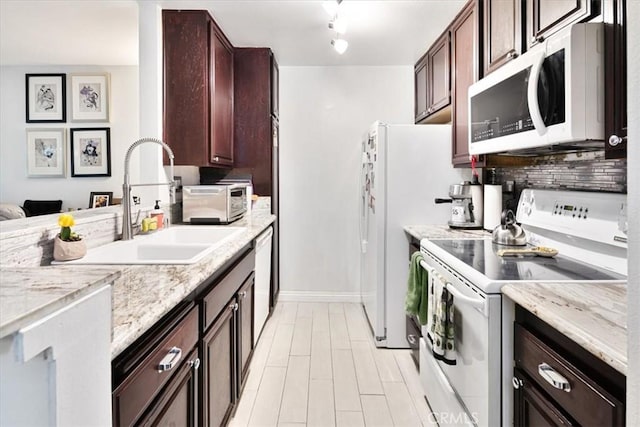 kitchen featuring backsplash, light stone counters, sink, and white appliances