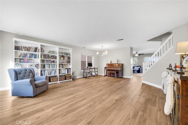 living area featuring hardwood / wood-style floors and ceiling fan with notable chandelier