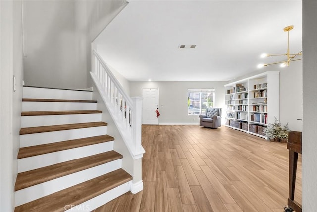 stairway with hardwood / wood-style flooring and a notable chandelier