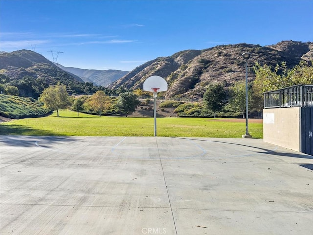 view of sport court featuring a mountain view and a yard