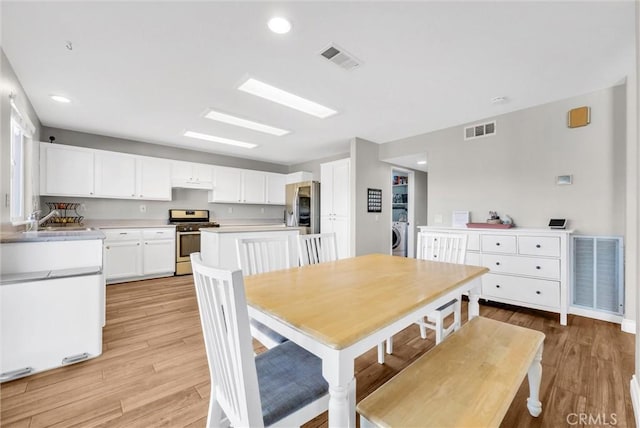 dining room featuring washer / clothes dryer, sink, and light hardwood / wood-style floors