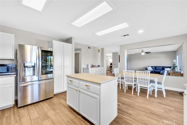 kitchen featuring ceiling fan, white cabinetry, stainless steel appliances, a kitchen island, and light wood-type flooring