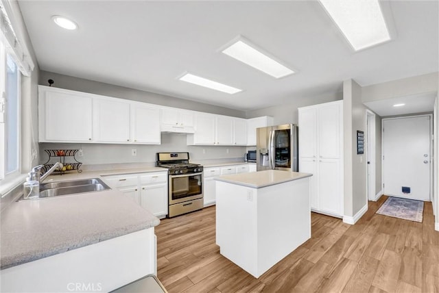 kitchen with light wood-type flooring, a center island, stainless steel appliances, and sink