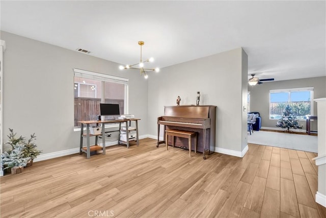 miscellaneous room featuring ceiling fan with notable chandelier and light hardwood / wood-style floors