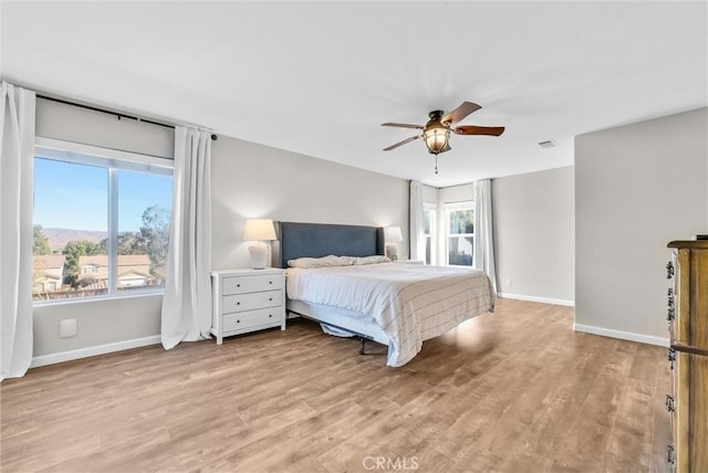 bedroom featuring ceiling fan, light hardwood / wood-style flooring, and multiple windows