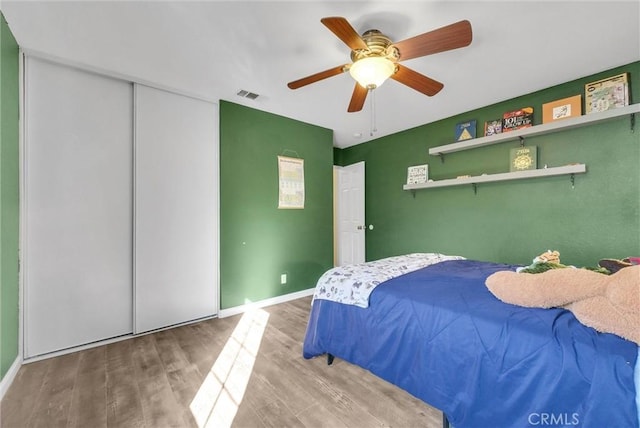 bedroom with hardwood / wood-style floors, a closet, and ceiling fan