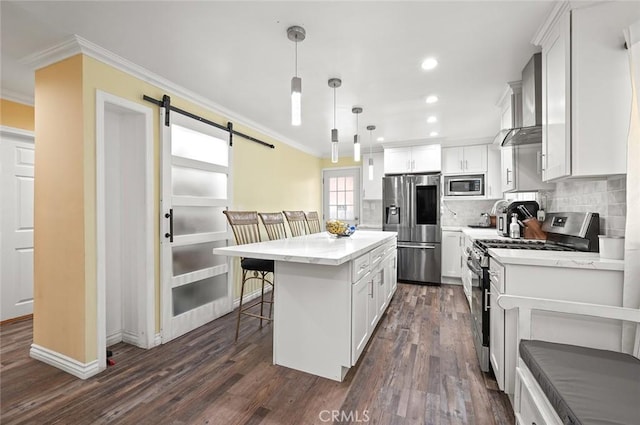 kitchen with white cabinetry, a center island, stainless steel appliances, a barn door, and decorative light fixtures