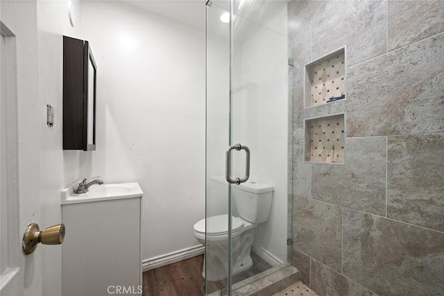 bathroom featuring vanity, hardwood / wood-style flooring, toilet, and a shower with shower door