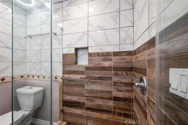 bathroom featuring a shower with door and toilet