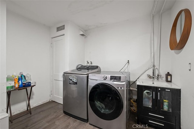 clothes washing area with dark hardwood / wood-style floors, sink, and washing machine and clothes dryer