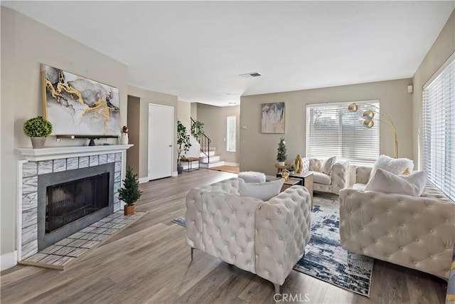 living room with light hardwood / wood-style floors, a wealth of natural light, and a tiled fireplace