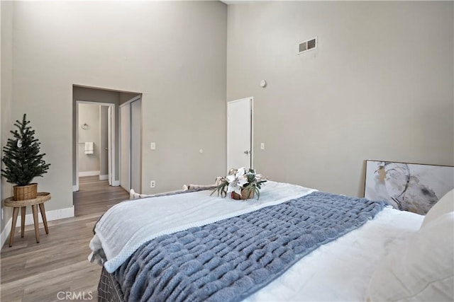 bedroom featuring wood-type flooring and a towering ceiling