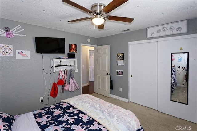 bedroom featuring ceiling fan, a closet, light carpet, and a textured ceiling