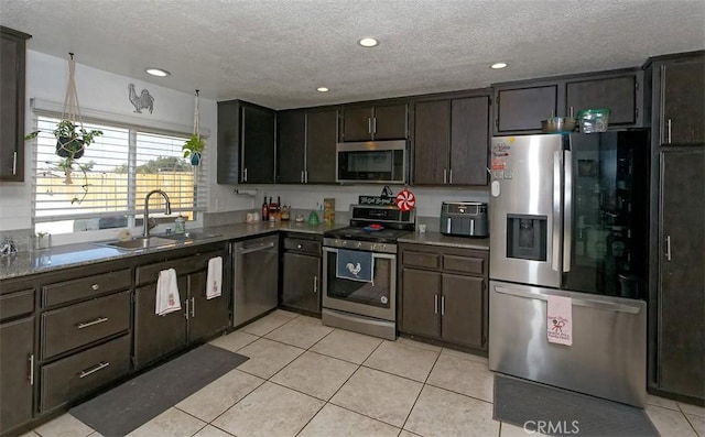 kitchen featuring sink, a textured ceiling, dark brown cabinets, light tile patterned flooring, and stainless steel appliances