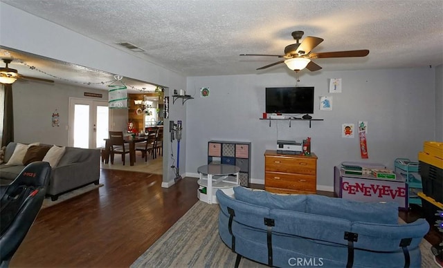 living room with a textured ceiling, ceiling fan, hardwood / wood-style floors, and french doors