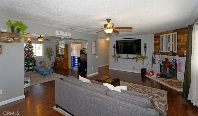 living room featuring ceiling fan, dark hardwood / wood-style flooring, and a textured ceiling