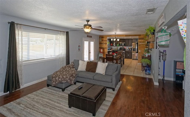 living room featuring ceiling fan, french doors, wood-type flooring, and a textured ceiling