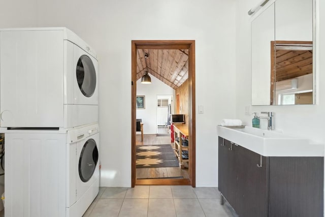 washroom featuring sink, light tile patterned floors, and stacked washer and dryer