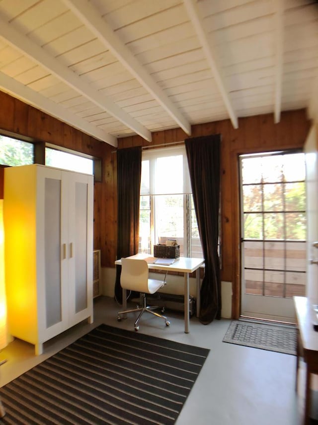 office space featuring vaulted ceiling with beams, wooden walls, and concrete flooring