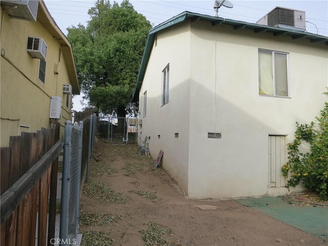 view of side of property with a wall unit AC and central AC