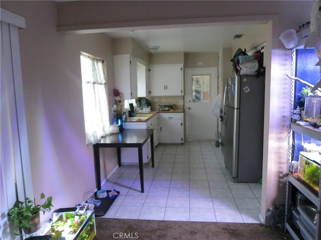 kitchen featuring white cabinetry, stainless steel refrigerator, and light tile patterned flooring