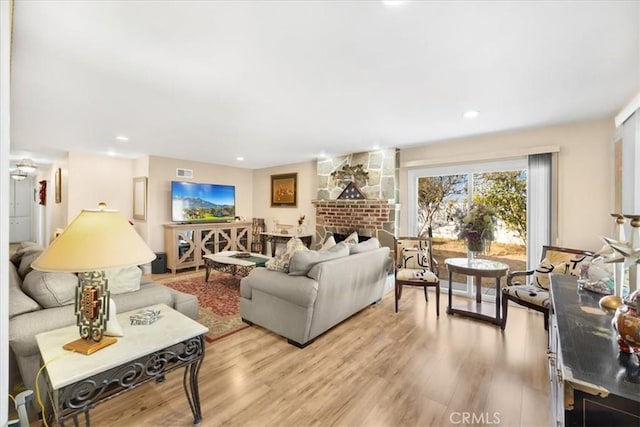 living room featuring light wood-type flooring and a brick fireplace