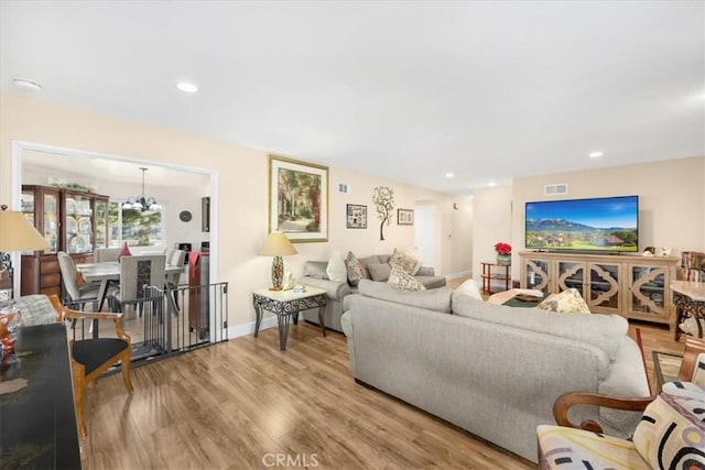 living room with light hardwood / wood-style flooring and an inviting chandelier