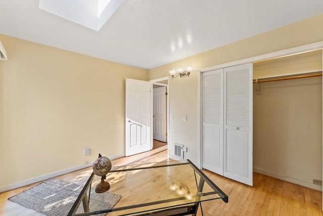 office area with a skylight and light hardwood / wood-style flooring