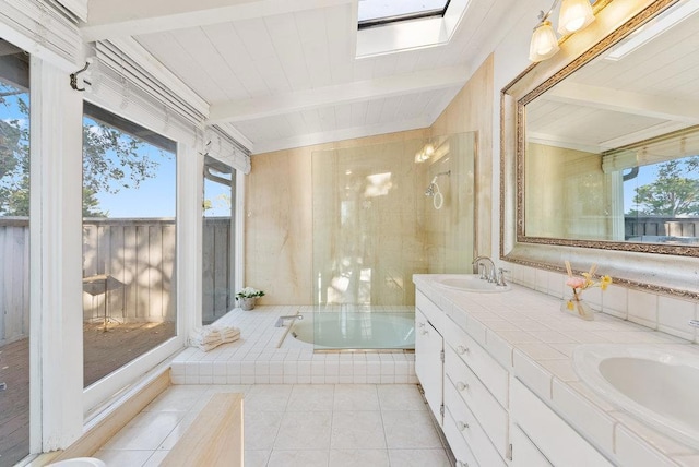 bathroom with a skylight, tiled tub, tile patterned floors, beam ceiling, and vanity