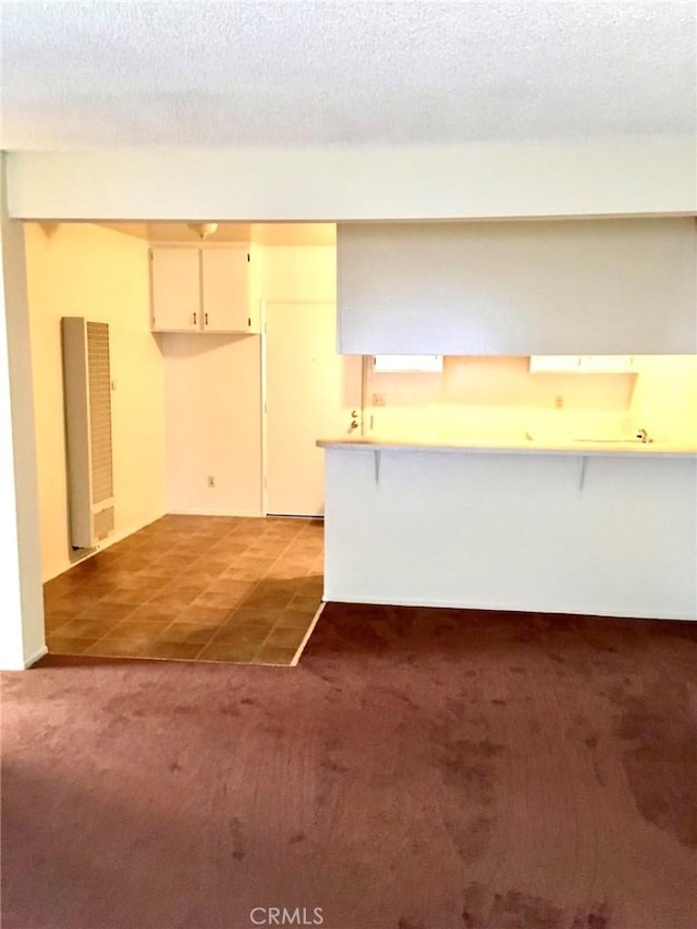 kitchen featuring a textured ceiling, kitchen peninsula, and light carpet