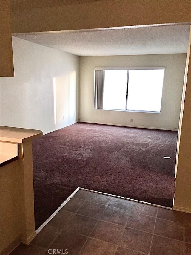 unfurnished room featuring dark colored carpet