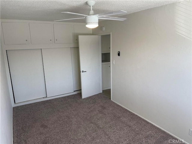 unfurnished bedroom featuring dark colored carpet, ceiling fan, a textured ceiling, and a closet