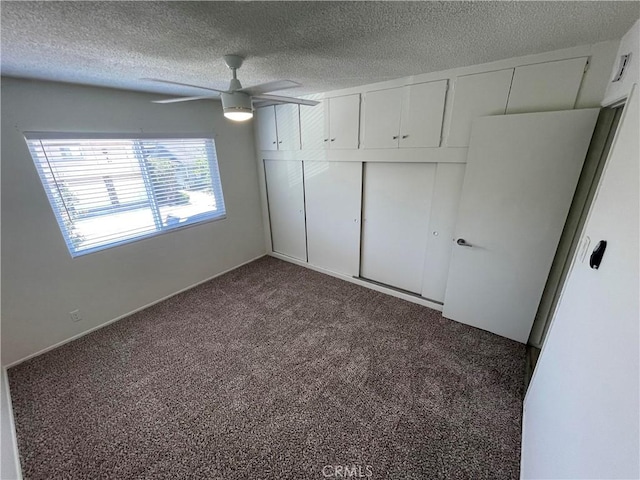 unfurnished bedroom with a closet, dark carpet, and ceiling fan