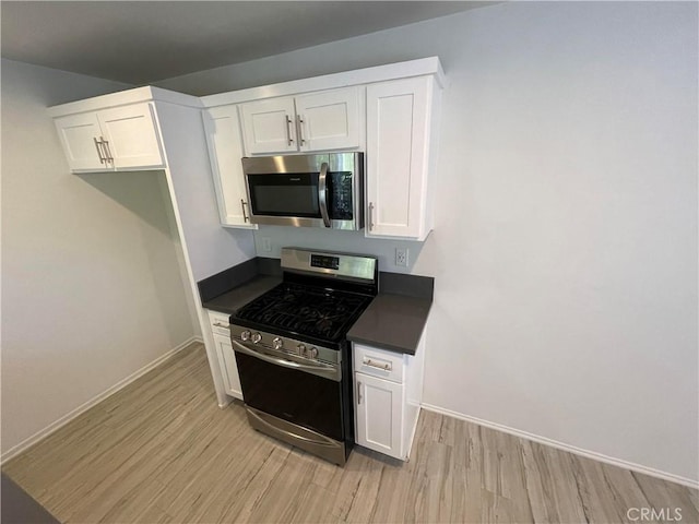 kitchen featuring appliances with stainless steel finishes, light hardwood / wood-style flooring, and white cabinetry