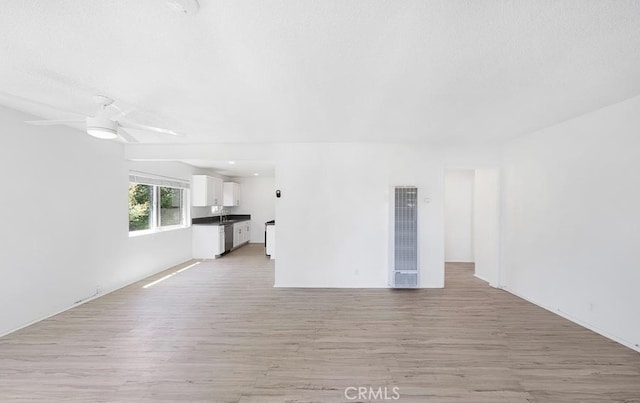 unfurnished living room featuring ceiling fan, light hardwood / wood-style flooring, and sink