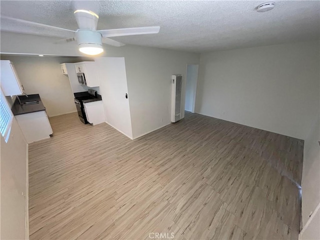 unfurnished living room with ceiling fan, light hardwood / wood-style flooring, a textured ceiling, and sink