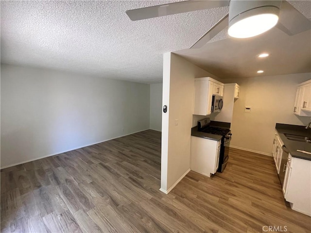 kitchen with sink, dark hardwood / wood-style floors, a textured ceiling, white cabinetry, and black range with gas cooktop